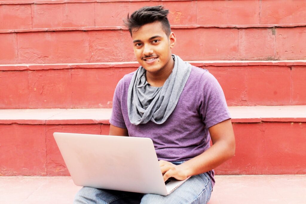 College student tracking budget on a laptop on a concrete bench