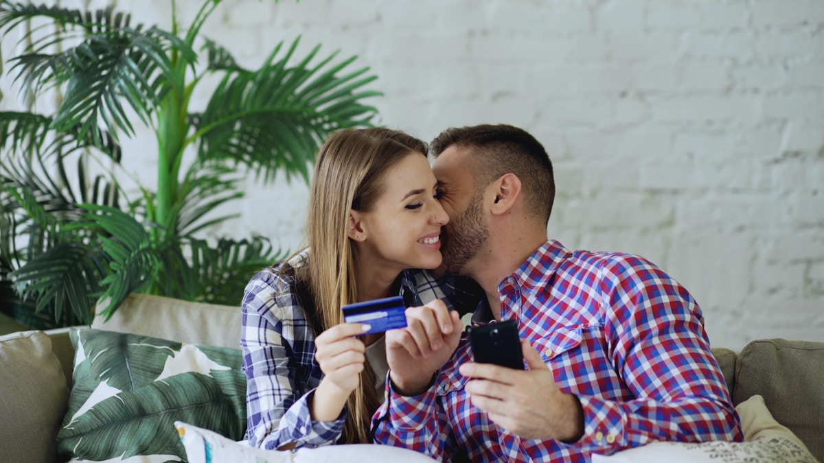 Couple discussing shared budgeting on a smartphone with credit card