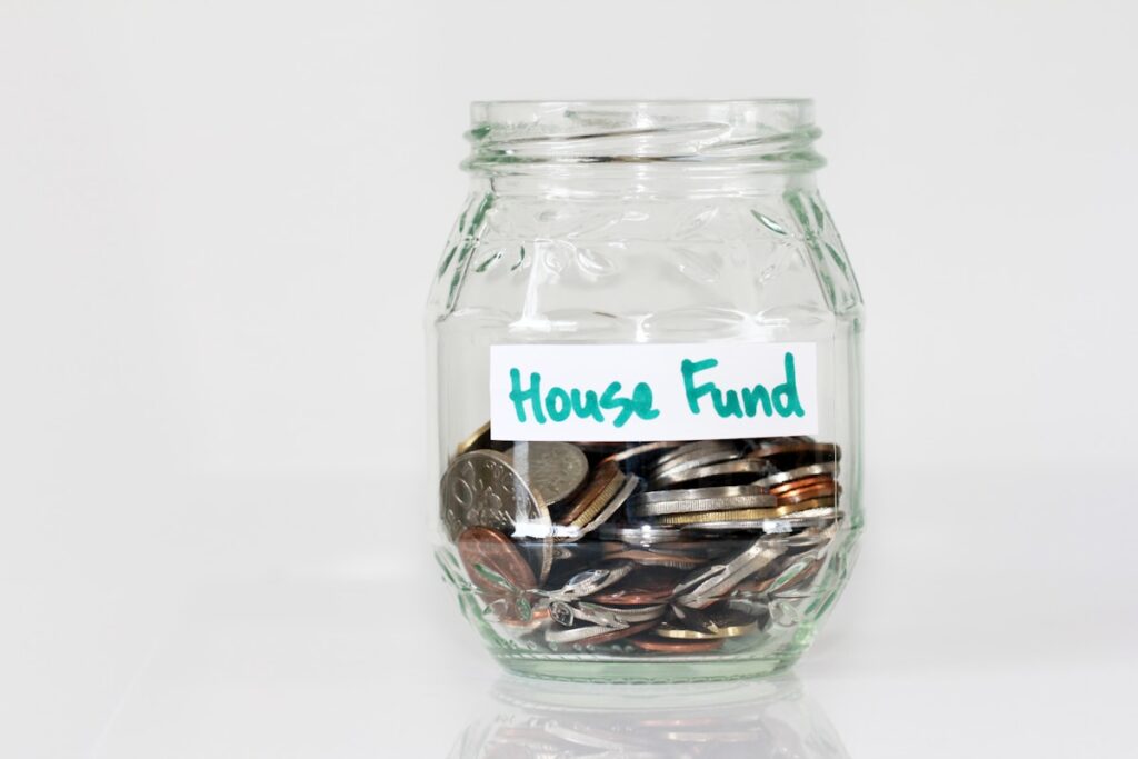 Glass jar of coins labeled fund as emergency savings
