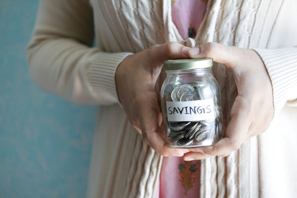 Woman holding glass jar labeled emergency fund savings