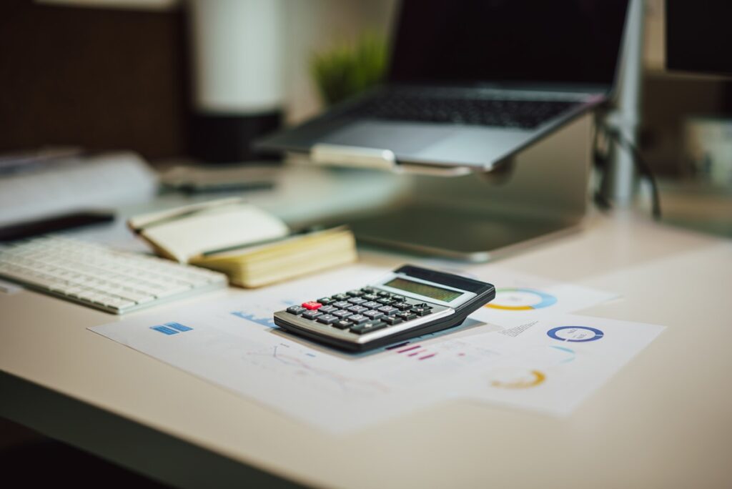 Calculator and laptop comparing iSave and Excel for budgeting