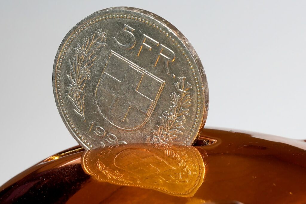 Hand placing coin into piggy bank illustrating the psychology of saving